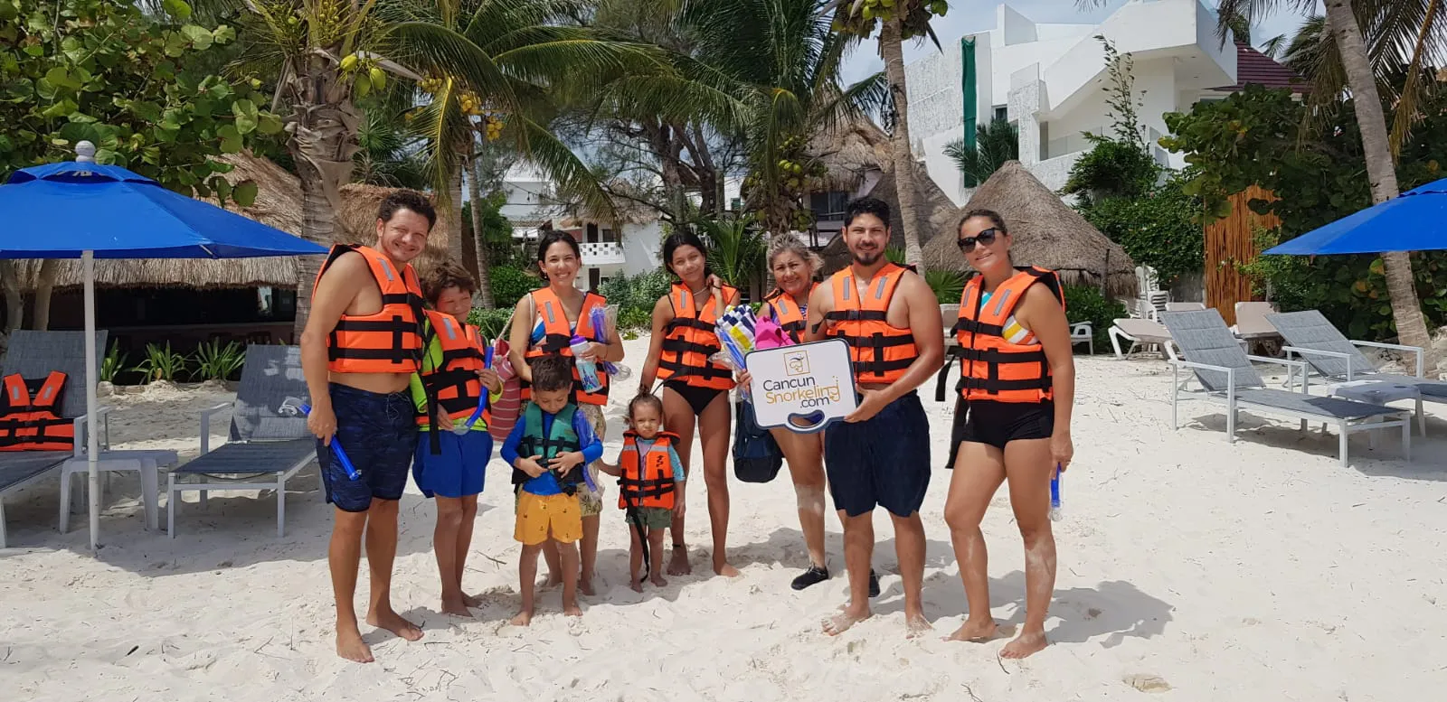 Una familia de seis adultos y tres niños parados enfrente de sillas de playa | Cancun Snorkeling
