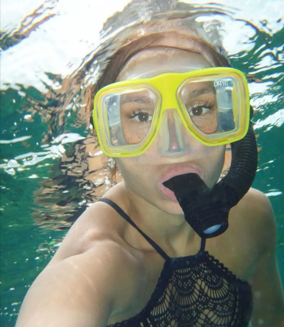 Mujer usando máscara de buceo y un tubo tomándose una foto bajo el agua | Cancun Snorkeling