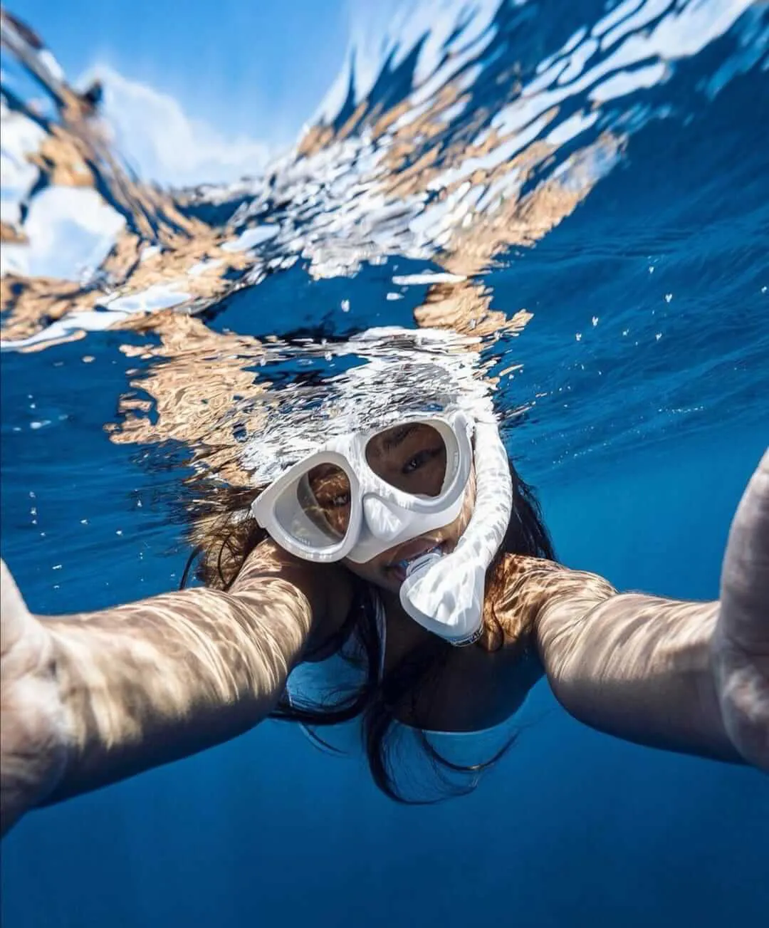 Mujer tomándose una foto bajo el agua con ambas manos mientras hace snorkel | Cancun Snorkeling