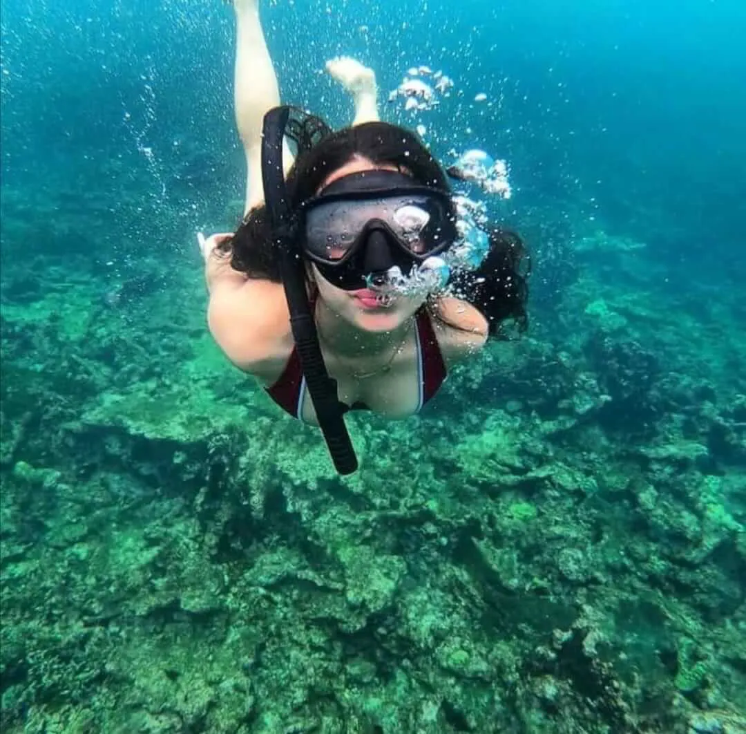 Snorkeler girl underwater throwing air in form of bubbles through her mouth and nose