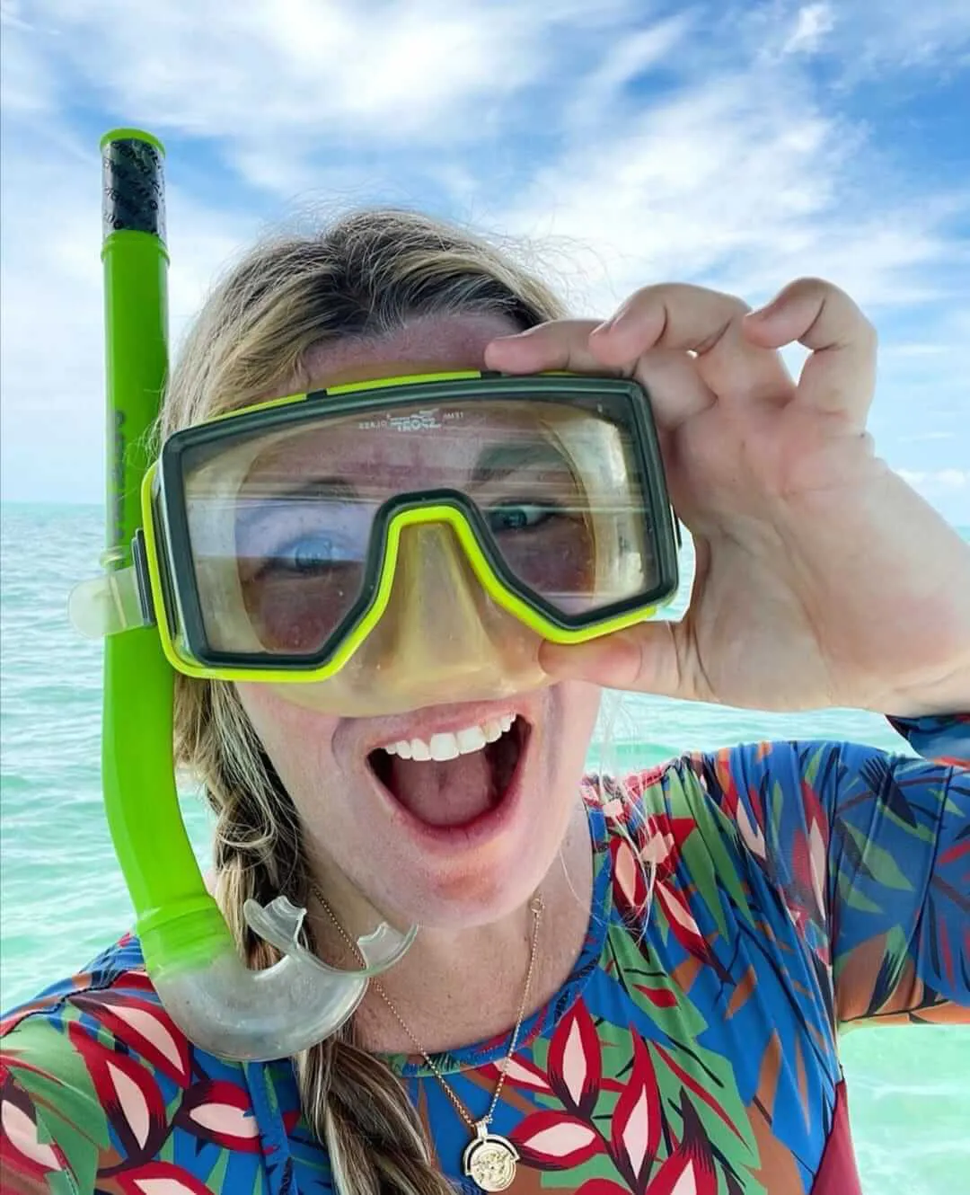 Blode snorkeler girl smiling at camera while wearing and holding her mask