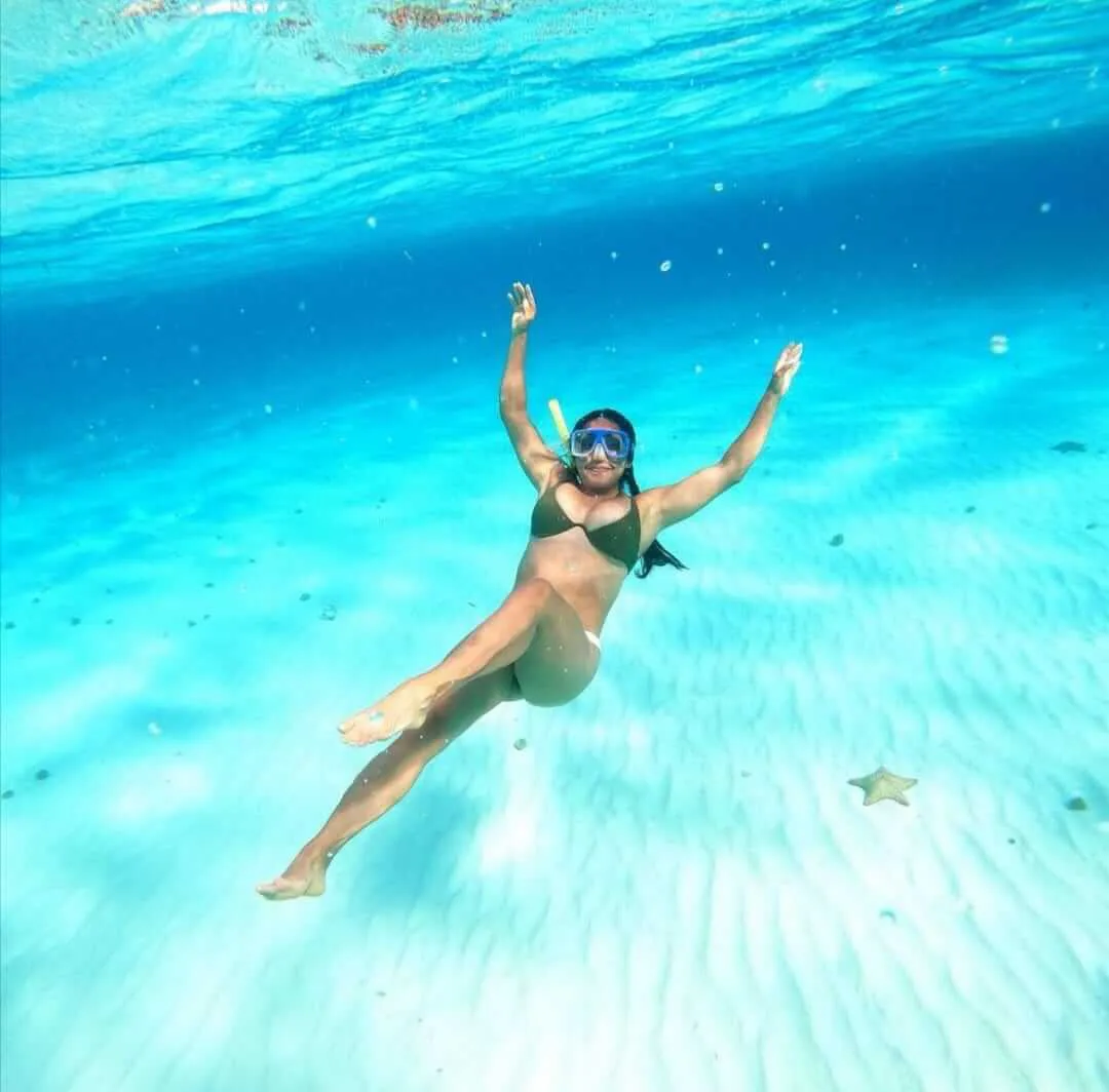 Mujer recostada en la arena en las profundidades del mar azul turquesa | Cancun Snorkeling