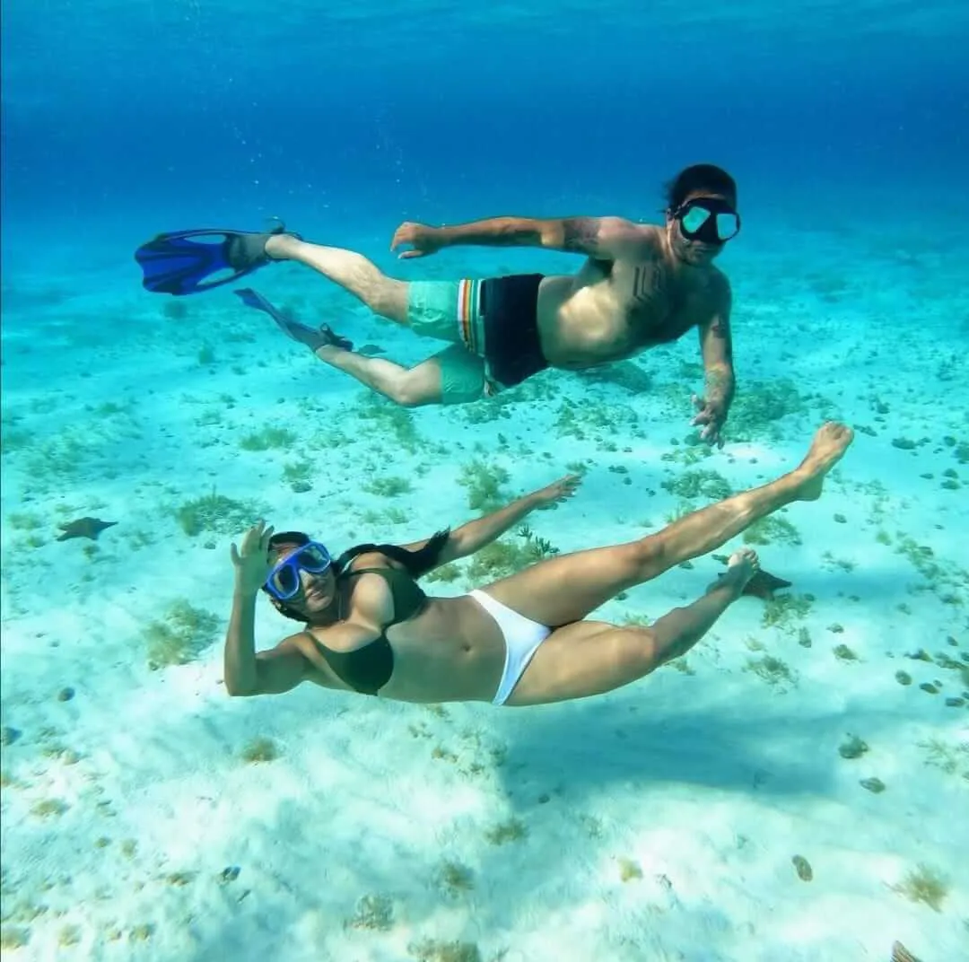Pareja haciendo snorkel en las profundidades del mar azul turquesa | Cancun Snorkeling