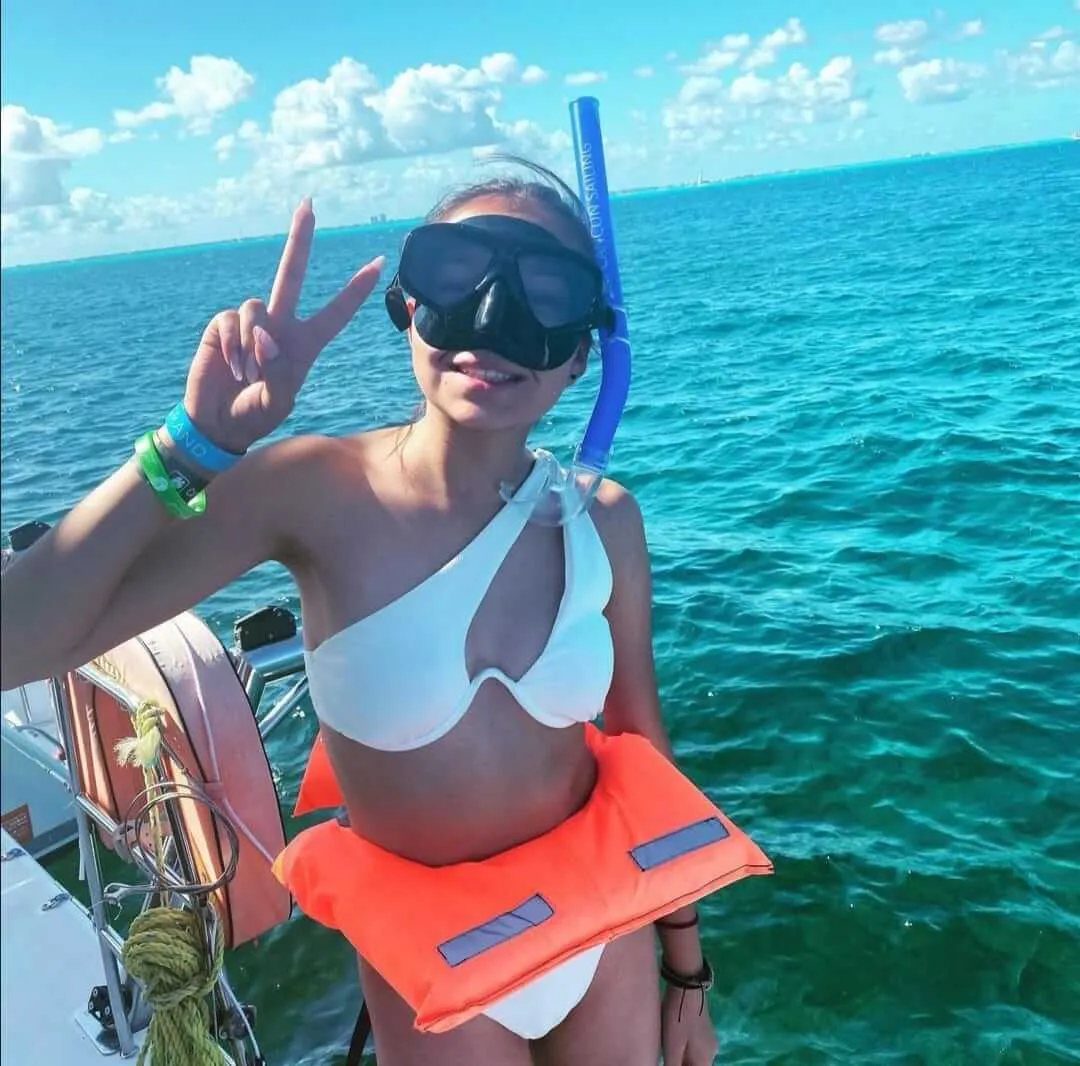 Mujer con traje de baño blanco haciendo snorkel con un chaleco salvavidas  lista para saltar al agua | Cancun Snorkeling