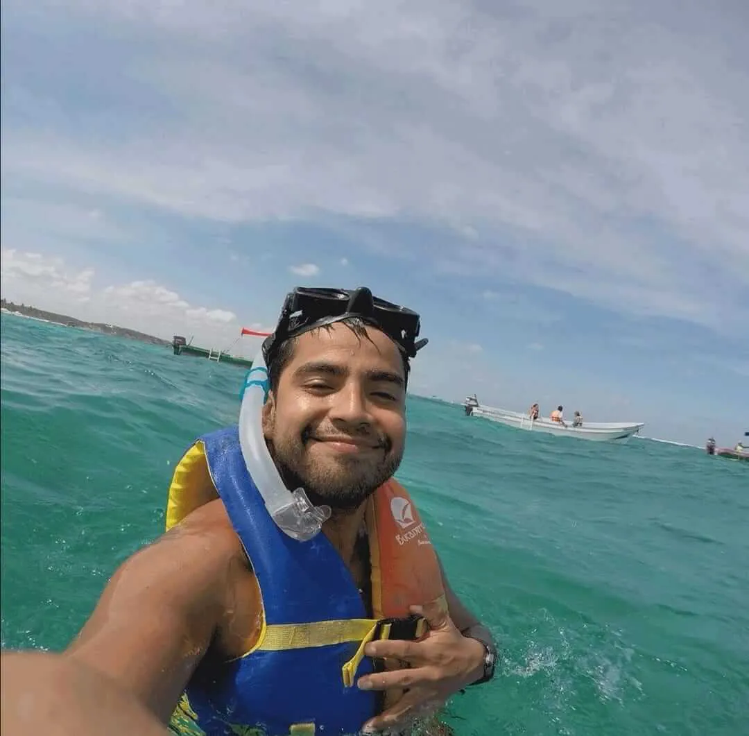 Hombre jóven tomándose una foto en el mar mientras usa un chaleco salvavidas y su equipo de snorkel | Cancun Snorkeling